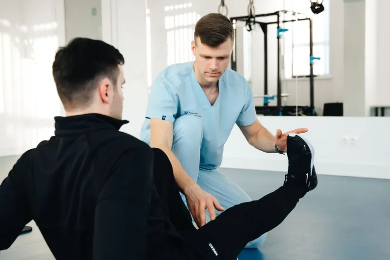 Fisioterapista che guida un paziente in un esercizio di rinforzo della gamba in palestra riabilitativa